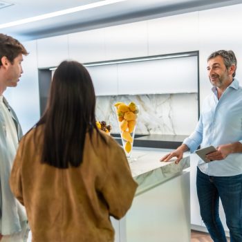 Couple and interior designer discussing kitchen furniture in showroom, focusing on modern design and functionality